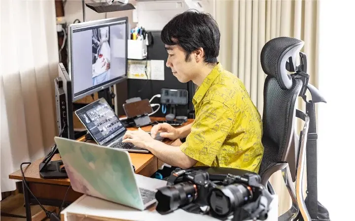 3つの画面を並べた机で、撮影した写真を選んでいる藤代誉士